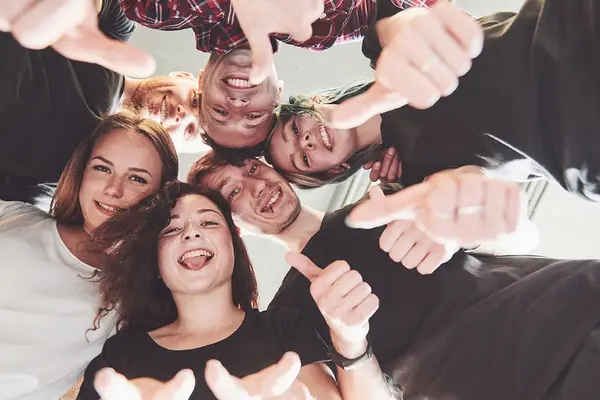 Eine gruppe Jugendliche bildet einen Kreis und sieht in die Mitte zum Foto 