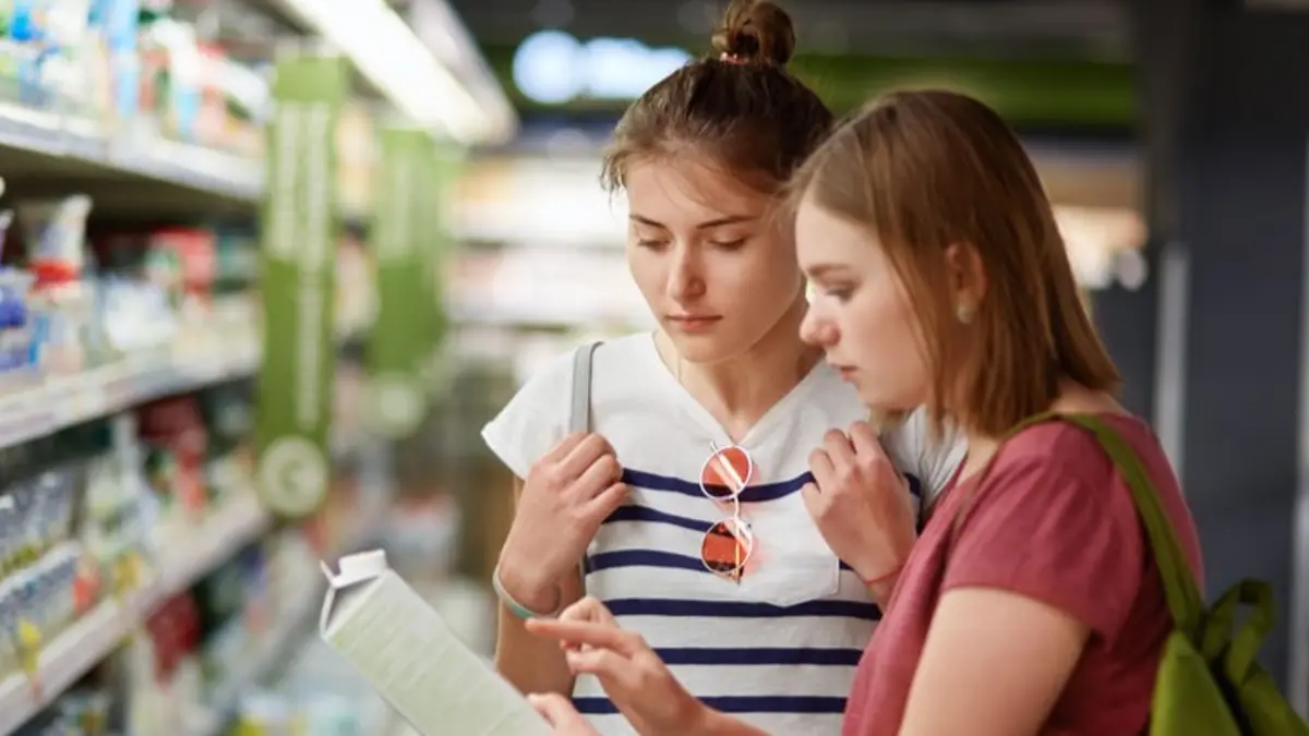zwei junge Frauen schauen eine Verpackung im Lebensmittelladen an