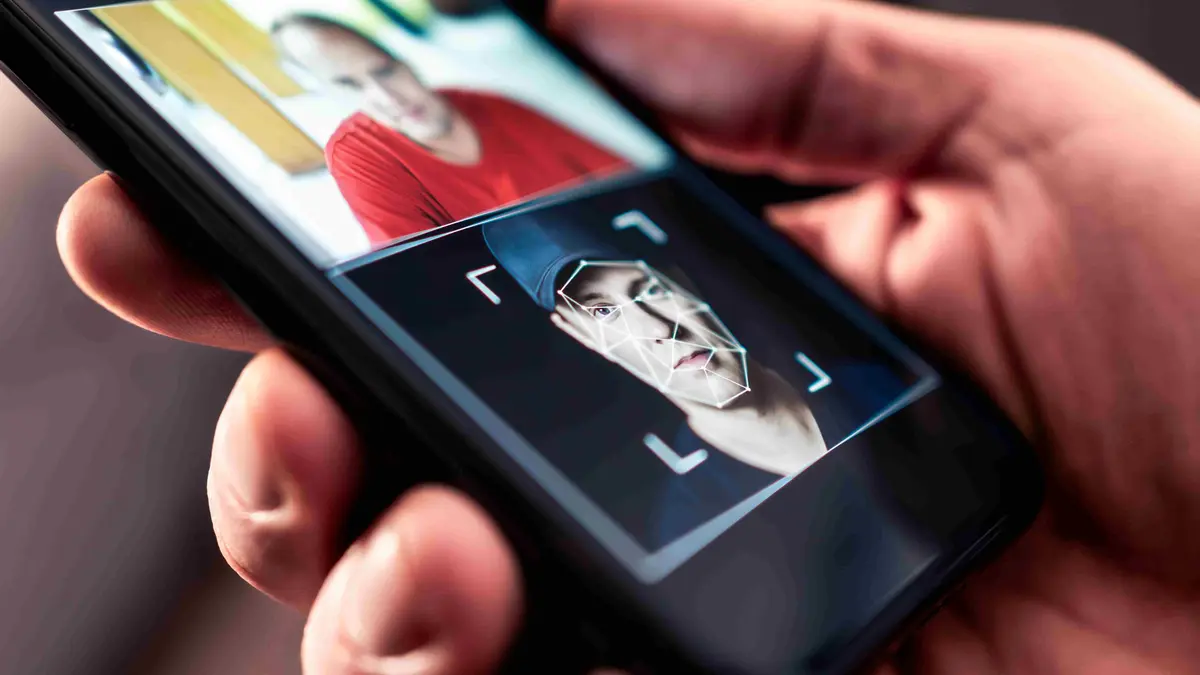 „Smartphone zeigt ein manipuliertes Porträt mit Deepfake-Technologie: Eine Person hält ein Handy, auf dessen Bildschirm ein Gesicht mithilfe künstlicher Intelligenz verändert wurde. Symbolbild für Deepfake, Gesichtstausch, Identitätsdiebstahl und KI-gestützte Bildbearbeitung.