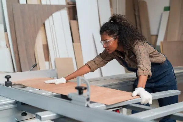 Eine Frau schneidet an einer Werkbank ein Stück Holz