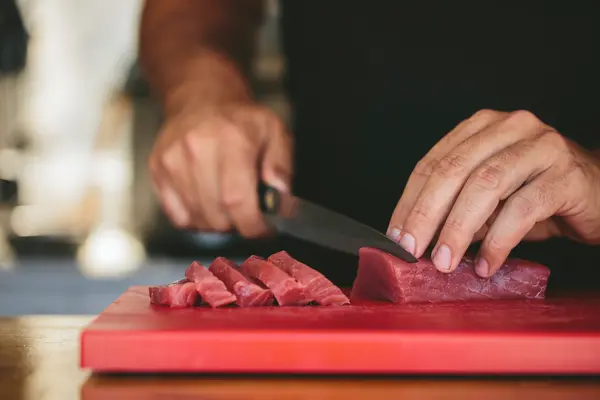 Hände schneiden Fleisch auf Küchenbrett