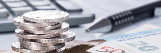 Münzen und Scheine und ein Taschenrechner auf dem Tisch