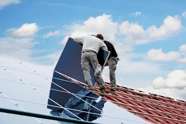 Zwei Handwerker montieren eine Solaranlage auf einem Hausdach