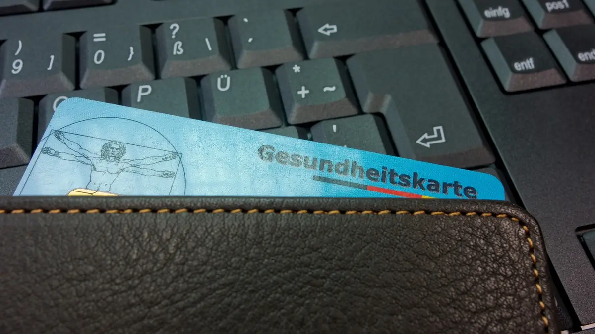 Blaue Krankenkassenkarte lieht auf einer Computer-Tastatur