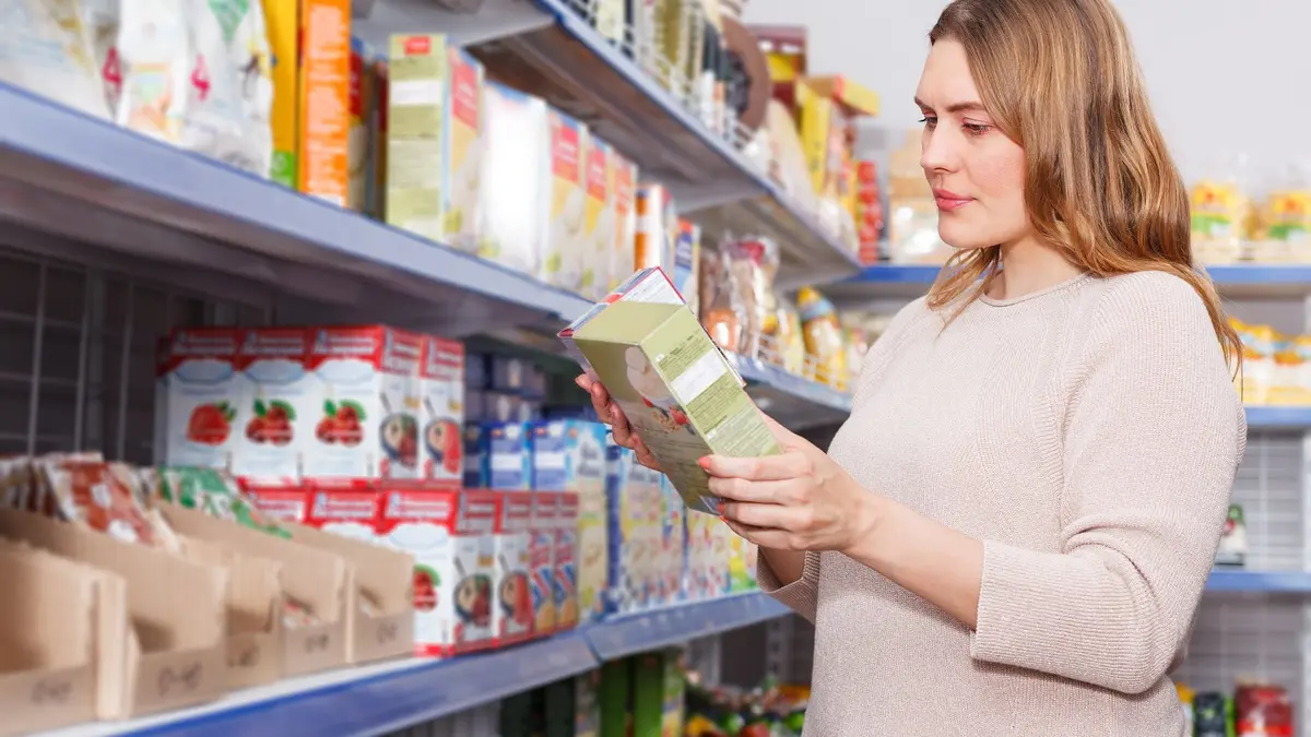 Eine Frau studiert Verpackungen beim Einkaufen in einem Supermarkt.