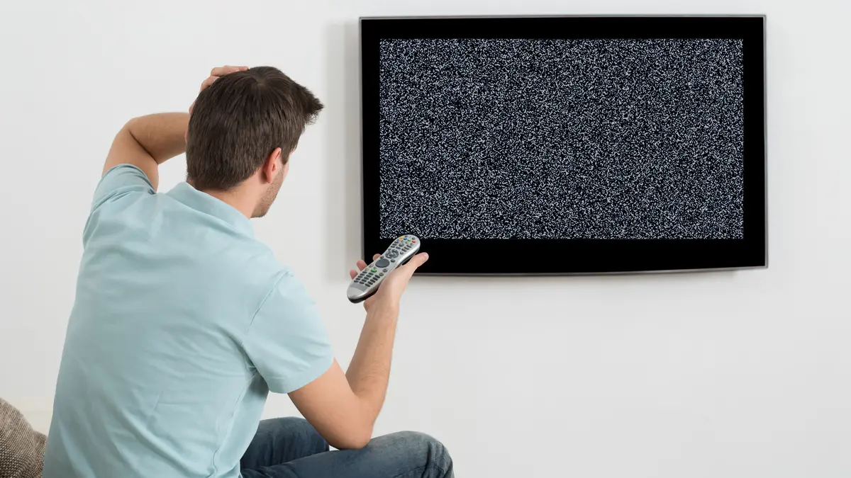 Mann sitzt vor defektem Fernsehgerät