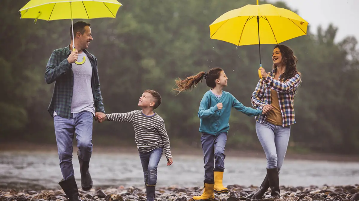Versicherungen für unterschiedliche Lebenslagen: Erwachsene und Kinder laufen im regen unter Regenschirmen