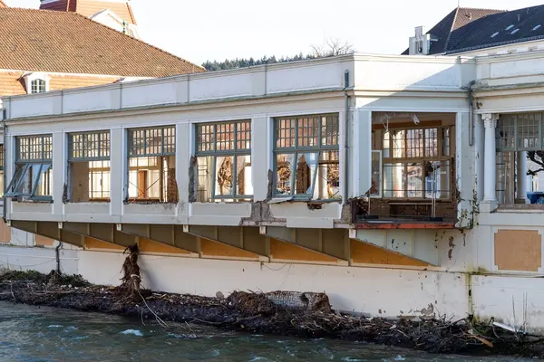 Ein halbzerstörtes Haus an einem Fluss.