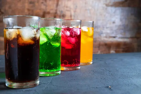 Bunte Getränke mit Eiswürfeln in hohen Gläsern.