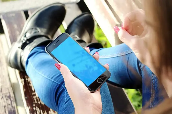 Frau auf Parkbank hält Smartphone in der Hand