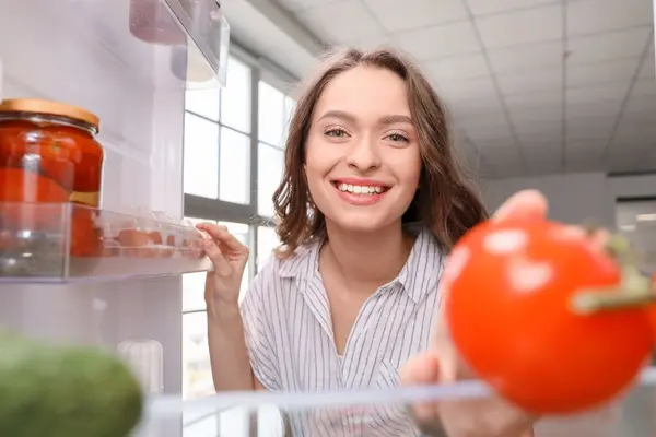 Frau öffnet den Kühlschrank