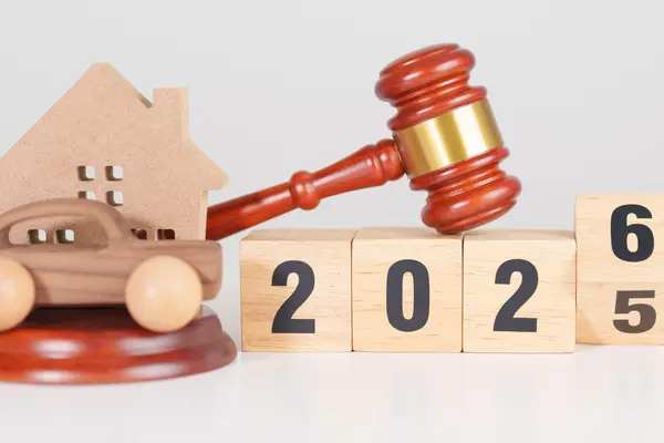 Holzspielzeug mit Aufschrift "2026" sowie ein Holzhaus, ein Holzauto und ein Gerichtshammer