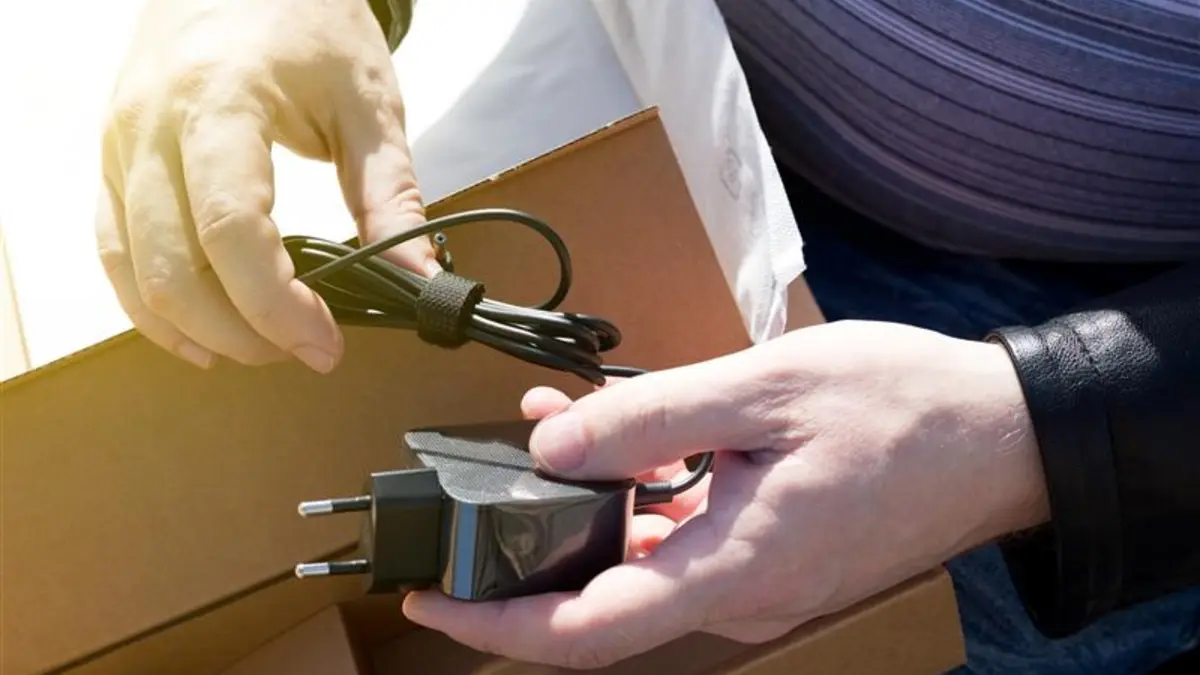 Hände packen aus einer Schachtel ein Kabel aus