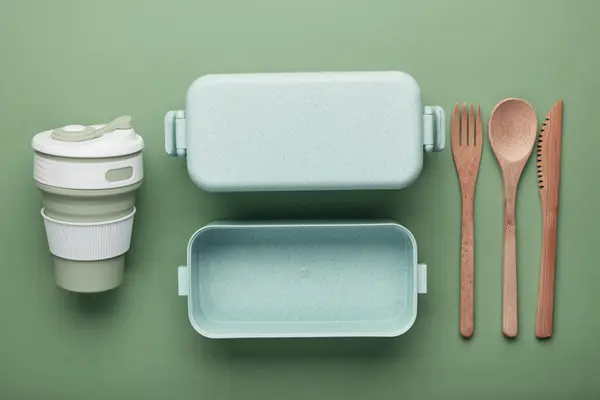 Schmuckbild: Plastik- und Holzgeschirrteile nebeneinanderliegend vor grünem Hintergrund