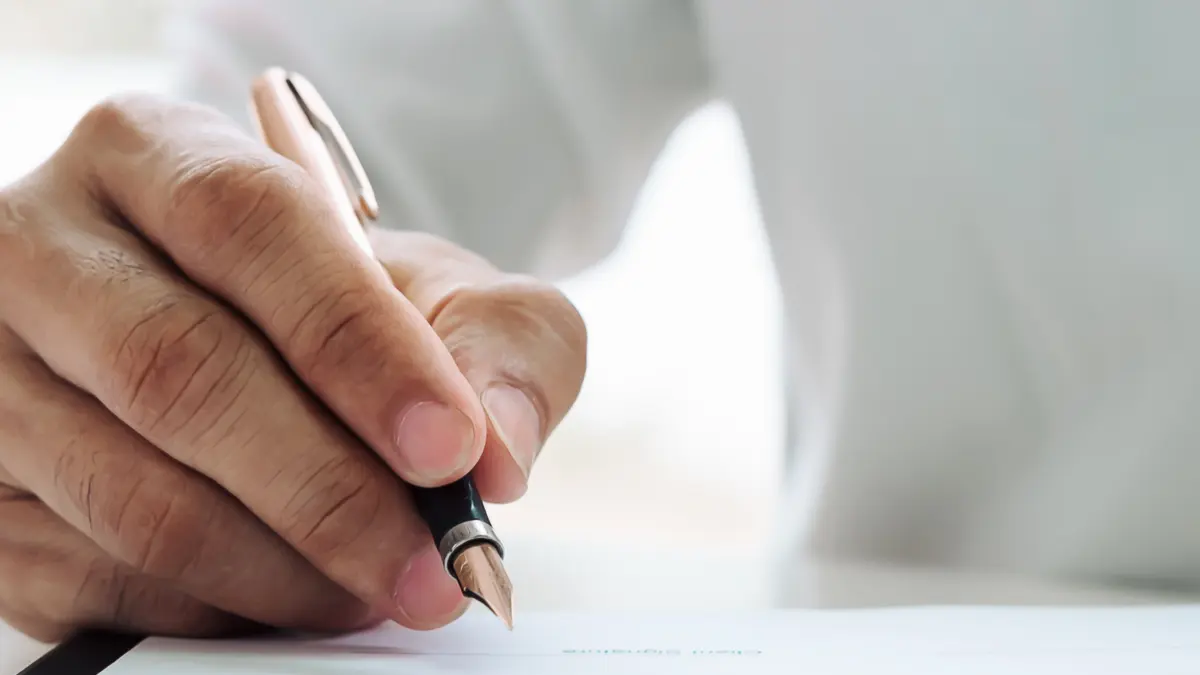 Eine Hand unterzeichnet ein Schriftstück