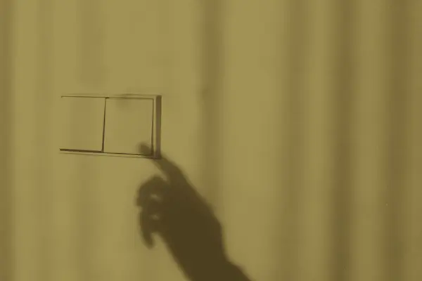 Schatten einer Hand betätigt Lichtschalter