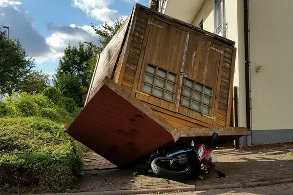 Ein Gartenhaus liegt auf dem Dach udn hat unter sich ein Motorrad begraben.