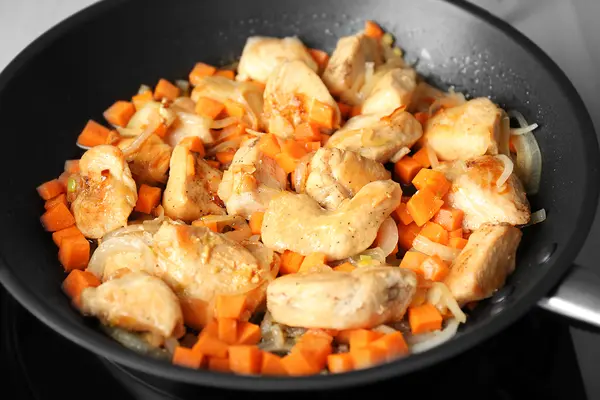 Hähnchen- und Kartottenstücke einer Bratpfanne.