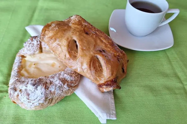 Zwei Gebäckstücke liegen auf einer Serviette, daneben eine Tasse Tee.