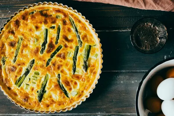 Eine Spargelquiche, daneben liegen Eier