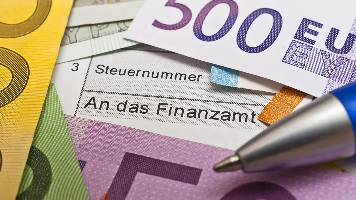 Steuerformular mit Schrift "Steuernummer" und "An das Finanzamt", auf dem Euro-Geldscheine und die Spitze eines Kugelschreibers liegen Foto: Stockfotos-MG / Fotolia.com