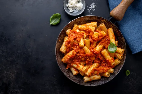 Nudeln in Tomatensauce auf einem dunklen Teller
