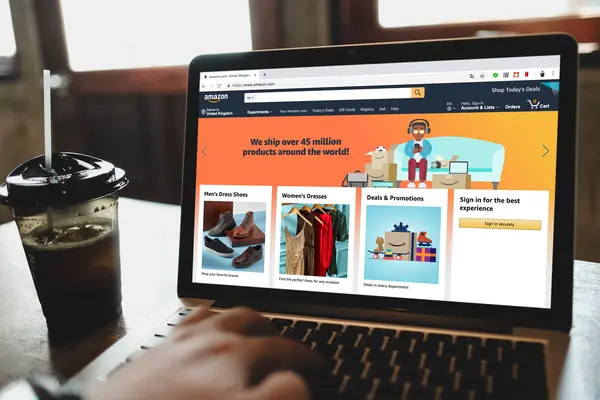 Person sitzt am Laptop und halt Amazon-Seite geöffnet