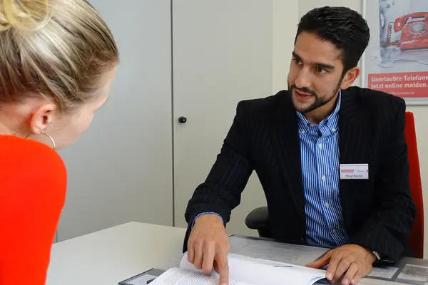 Mann berät eine Frau an einem Tisch