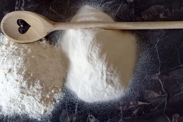Instantmehl auf einer Arbeitsfläche, daneben liegt ein Holzkochlöffel