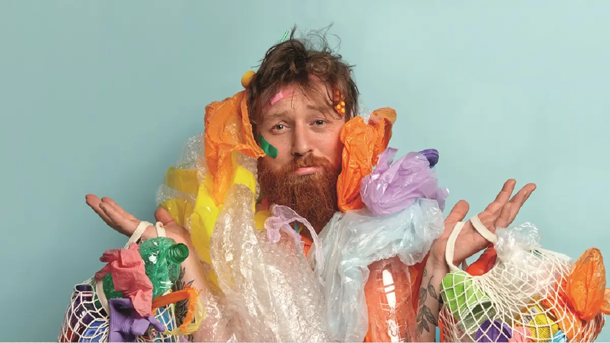 Mann mit Plastiktüten und Plastikflaschen behängt.
