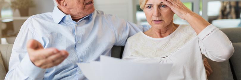 Älteres Ehepaar schaut entsetzt auf Dokumente