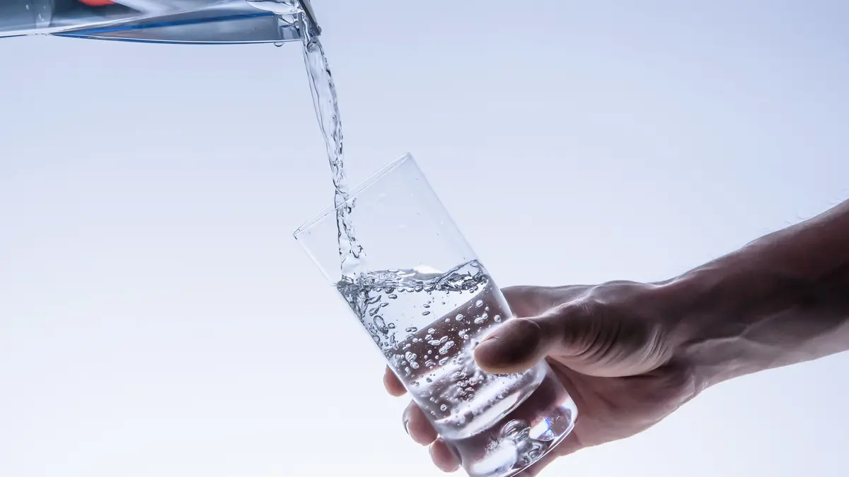 Glas Wasser wird aus Karaffe gefüllt