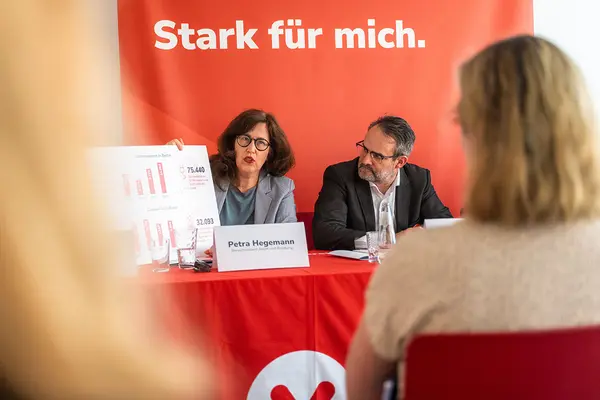 Petra Hegemann hält auf dem Podium der Jahrespressekonferenz Schild mit einer Grafik zu Energiesperren in Berlin. Daneben Markus Kamrad.