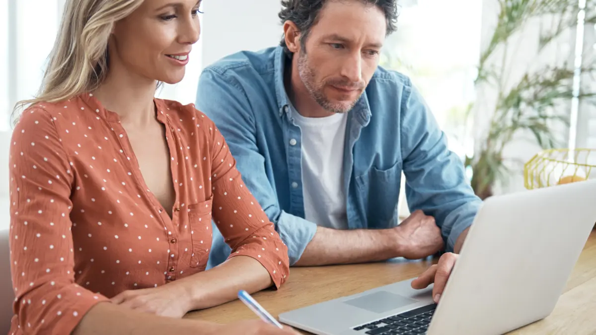 Eine Frau und ein Mann sitzen an einem Tisch und schauen auf einen Laptop