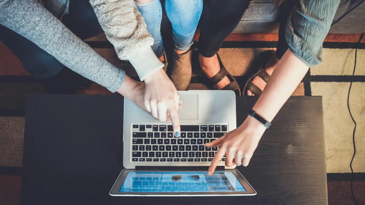 Personen zeigen auf einen Laptop