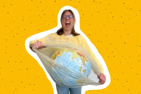 eine junge Frau zerreißt die Plastikhülle, in die ein Modell der Erde eingepackt ist