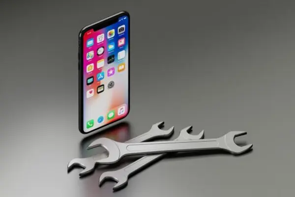 Handx mit Apps drauf und Schraubenschlüssel liegen davor. Der Hintergrund ist grau.
