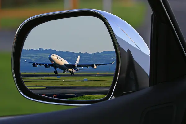 Flugzeug spiegelt sich im Rückspiegel eines Autos