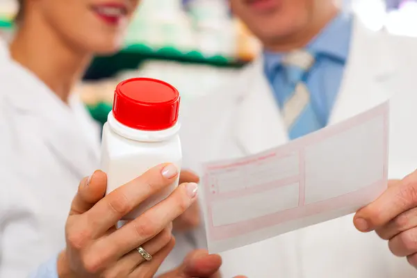 Eine Frau hält eine Pillendose, ein Mann ein Rezept in die Kamera