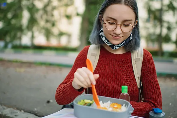 Eine junge Frau isst aus einer Lunchbox
