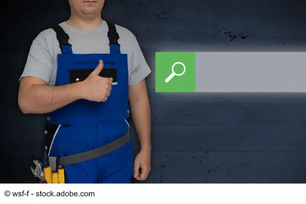 Ein Arbeiter in Arbeitskleidung mit Werkzeug am Gürtel steht symbolisch für die Online-Suche nach Handwerkern.