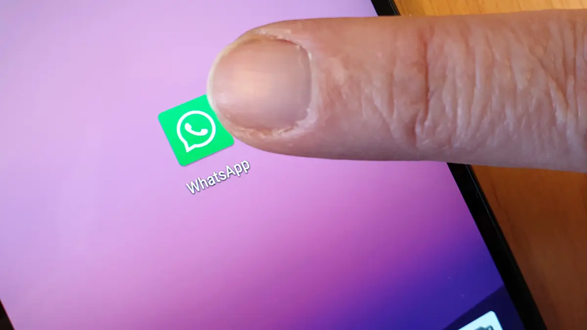 Ein Finger tippt aufs WhatsApp-Logo auf einem Smartphone-Display