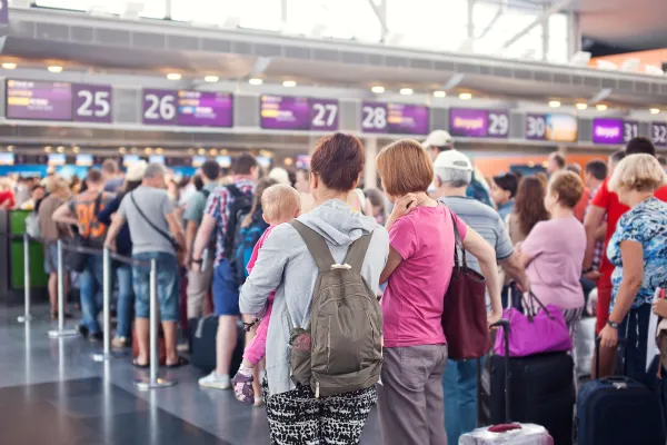 Eine Schlange von Menschen steht vor einem Schalter am Flughafen.