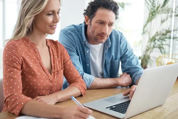 Eine Frau und ein Mann sitzen an einem Tisch und schauen auf einen Laptop