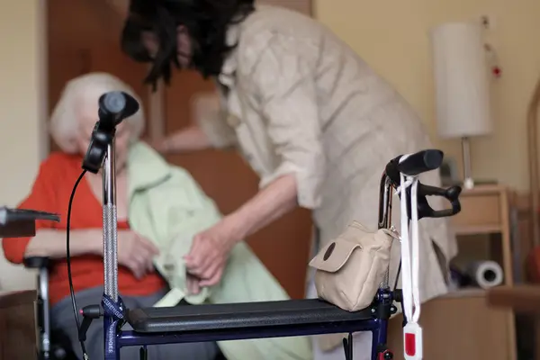 Rollator steht vor Seniorin und Pflegerin