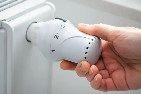 Heizung, mit Hand die am Regler dreht