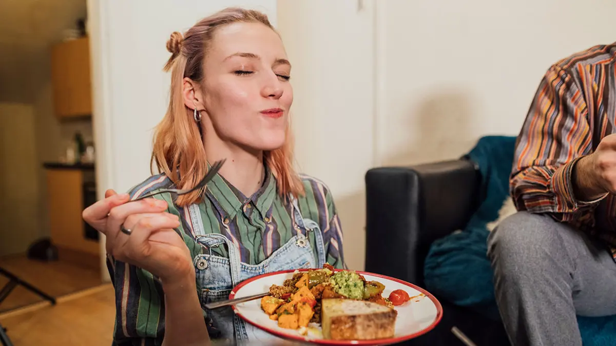 Eine junge Frau schließt beim Essen genießerisch die Augen