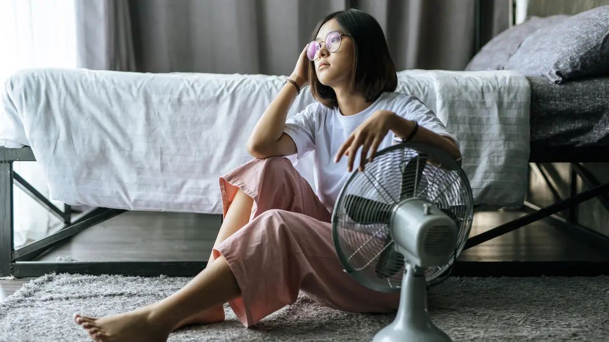 Eine Frau sitzt auf dem Boden vor einem Ventilator