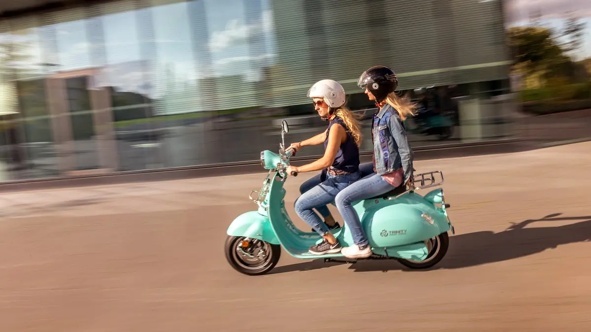 Zwei Frauen mit Helm auf einem E-Roller E-Scooter
