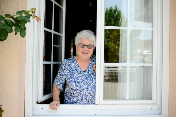 Seniorin steht am Fenster